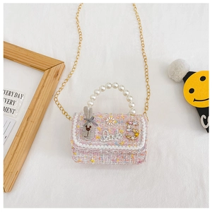 Detail of pink tweed girl's purse with pearl handle, gold chain and cute bunny charm