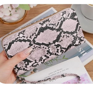 Close-up of snake skin pattern texture on pink and black long zipper wallet with wrist strap