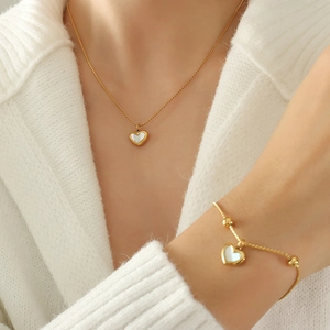 Elegant gold heart necklace and bracelet set with white shell inlay on model
