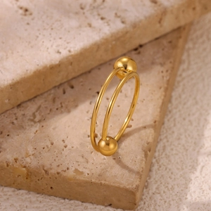 Close-up of 18k gold spiral ring with polished beads on a travertine stone surface