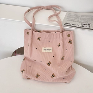 Detail of pink corduroy tote bag featuring a cute brown bear embroidery and woven label
