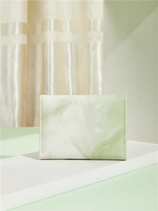Detail of light green marble texture and stitching on small faux leather wallet