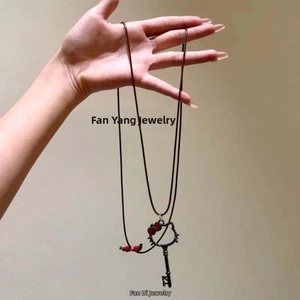 Detail of Hello Kitty style black key pendant with red bow on a wax cord necklace