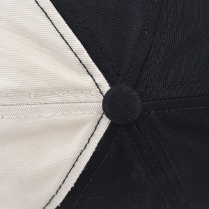 Macro shot of cotton baseball cap top showing black and white stitched panel details