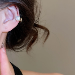 Macro side view of a minimalist gold ear cuff featuring a large round white pearl