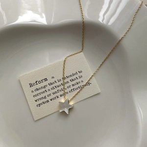 Close-up of a gold star necklace with mother of pearl inlay on a ceramic heart plate