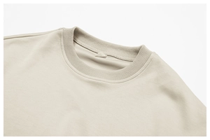 Gros plan sur le col rond côtelé d'un sweat-shirt beige au design minimaliste