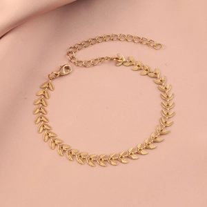 Elegant gold-plated leaf bracelet with lobster clasp on pink silk background
