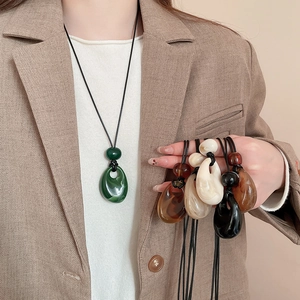 Close-up showing colorful acrylic water drop pendants with woven cords on a neck