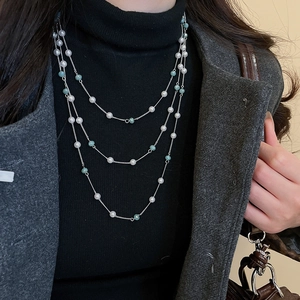 Dettaglio di una collana d'argento a strati con perle bianche e perline turchesi