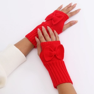 Detail of red knit fingerless gloves featuring a cute bow and cozy ribbed texture
