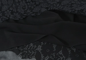 Dettaglio ravvicinato del pizzo nero e delle texture in chiffon sulla canotta nera
