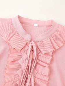Detailed close-up of pink chiffon shirt featuring ruffle collar and drawstring neckties