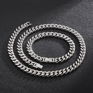 Macro shot of polished silver Cuban link chain necklace and bracelet set on black background