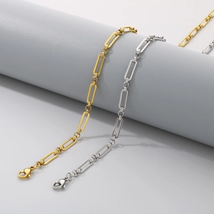 Détail de bracelets à maillons plats minimalistes dorés et argentés sur un support