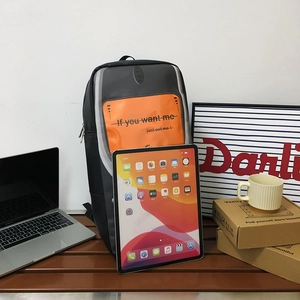 Minimalist black waterproof backpack with orange transparent pocket on wooden bench
