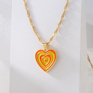 Gold-plated 18K necklace with orange and yellow heart enamel pendant on a white stand