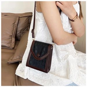 Gros plan sur un mini sac à bandoulière tressé noir avec garniture en cuir marron foncé