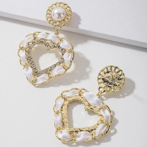 Gros plan de boucles d'oreilles cœur avec perles, ruban blanc et cristaux brillants