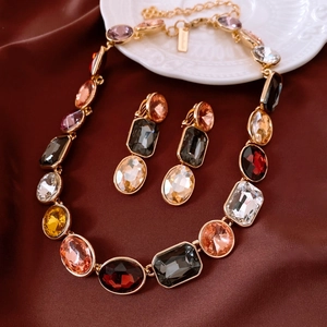 Detail of vintage gold jewelry set with colorful crystals on red silk background