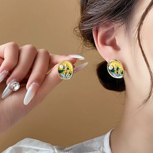 Detail of vintage enamel earrings with yellow floral pattern and small pearl on gold frame