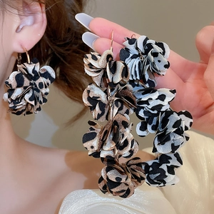 Close-up of fabric flower earrings with leopard and cow print petals on metal hooks