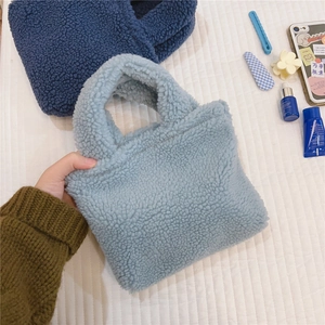 Détail de texture pelucheuse des mini sacs à main en peau de mouton bleue claire et foncée