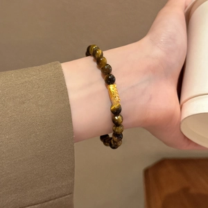 Detailed view of 18K gold-plated beads and tiger eye stone bracelet on a model wrist