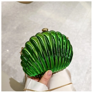 Close-up of green shell-shaped acrylic handbag with gold chain and glossy finish