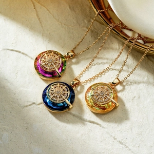 Elegant gold necklaces with round purple, blue, and yellow crystals on stone background