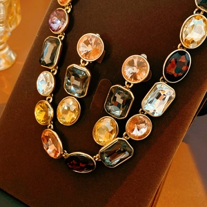 Dettaglio del set collana e orecchini vintage con cristalli su supporto di velluto marrone