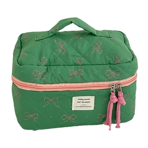 Quilted green cosmetic bag with pink bow patterns and dual zipper closure for travel