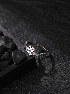 Macro detail of silver stainless steel ring featuring hollow flower pattern on dark stone