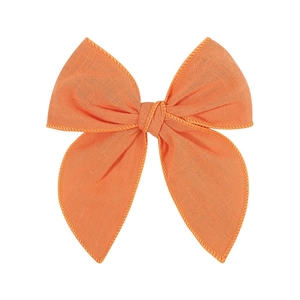 Detailed texture of orange cotton linen hair bow clip for girls on white background