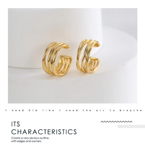 Detail of gold-plated multi-layer hollow C-shaped ear cuffs on a minimalist pedestal