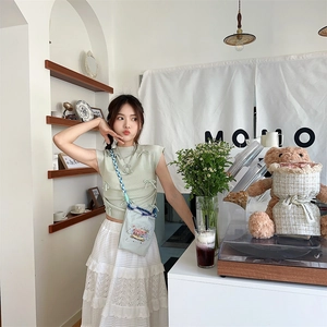 Girl in mint green bow vest and tiered white lace skirt with a small crossbody bag