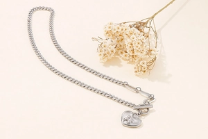 Detail view of silver heart pendant necklace with T-bar clasp and engraved figures