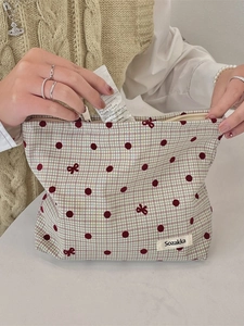 Beauty case a quadretti con pois e ricamo a fiocco rosso usato da una donna
