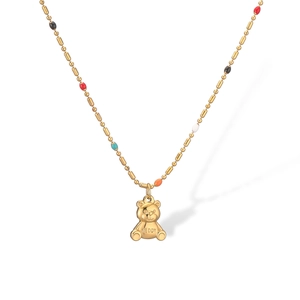 Detail of gold beaded necklace with a teddy bear pendant featuring TEDDY engraving
