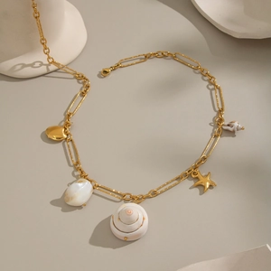 Détail du collier à chaîne trombone dorée avec des breloques de coquillages et d'étoiles