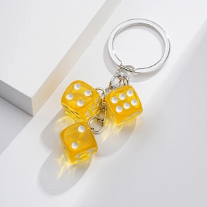 Detail of yellow translucent resin dice keychain with three dice on silver metal chain