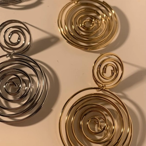 Modern gold and silver spiral drop earrings with sleek concentric circular metal design