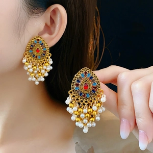 Gros plan détaillé de boucles d'oreilles vintage dorées avec émail et glands de perles