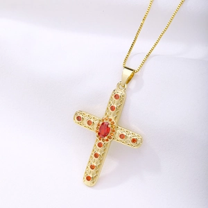 Detailed shot of golden cross pendant with orange crystals and red oval gemstone on silk