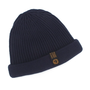 Detail of navy blue ribbed beanie featuring a sewn black label with gold lion emblem