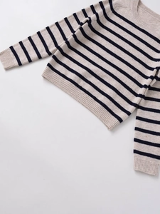 Detail of crewneck striped knit sweater showing navy stripes on beige ribbed fabric