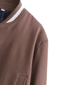 Close-up of the striped ribbed collar and shoulder stitching on a brown baseball jacket