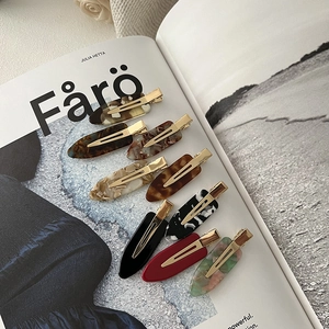 Flat lay of 8 assorted cellulose acetate hair clips with marble patterns on a magazine