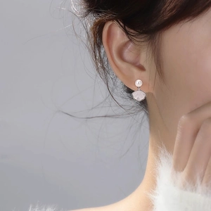 Detailed view of elegant shell earrings with white pearl on model's ear profile