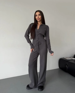 Detail of grey knitted two-piece set featuring a buttoned cardigan and wide-leg trousers